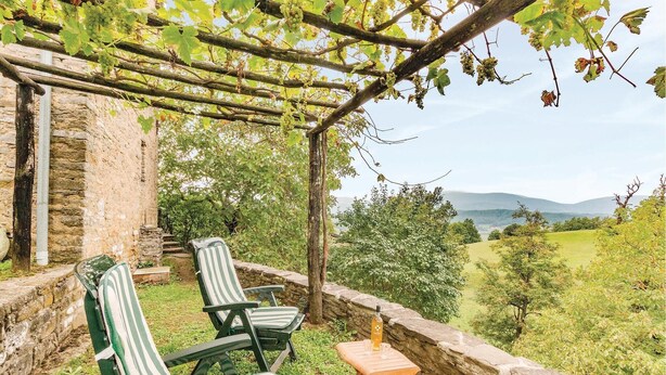 A covered outdoor seating area with two striped chairs and a small table, overlooking a vineyard and distant hills. - Awesome home in Borgo Val di Taro PR with WiFi (Borgo Val di Taro PR)