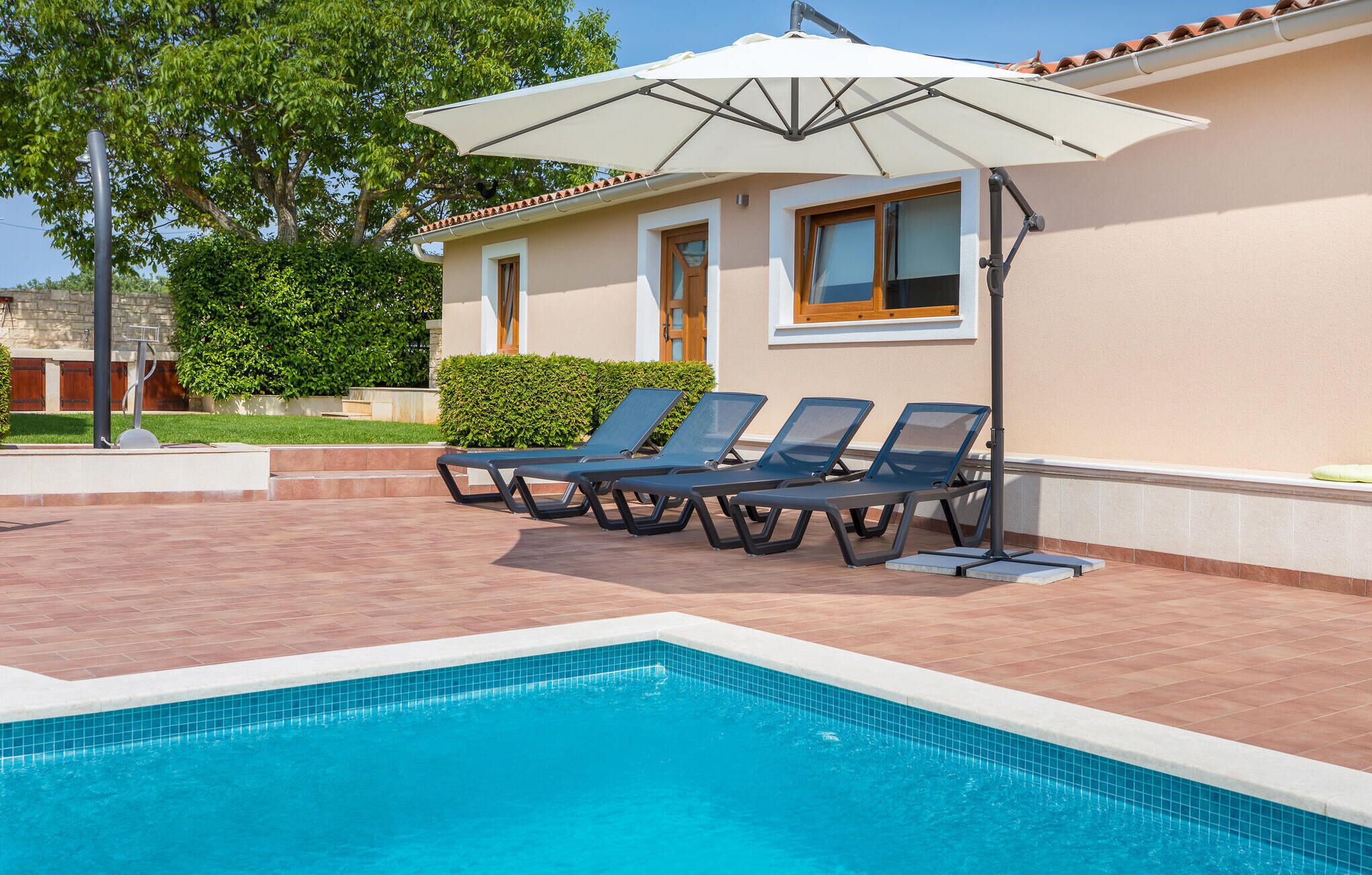 A swimming pool with lounge chairs and an umbrella.