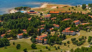 An aerial view of a coastal residential area with houses, a swimming pool, and a beach. - Studio with outdoor pool (Umag)