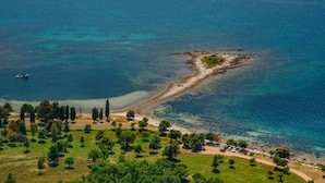 An aerial view of a coastal area with a small island, clear blue waters, and a path leading to the beach. - Studio with outdoor pool (Umag)