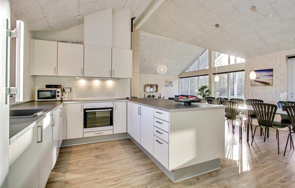 Enjoy cooking in this kitchen with a central island, appliances, and large windows offering a view of the outdoors.