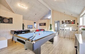 Relax and play in this spacious indoor recreation area featuring a pool table, foosball table, and bar.