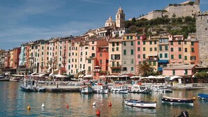 A waterfront with colorful buildings, a historic tower, and boats docked along the quay.
