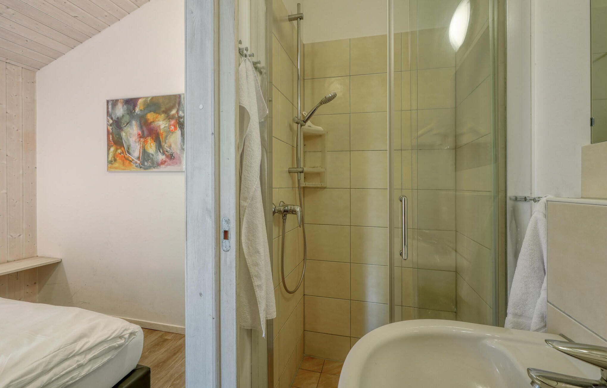 Une salle de bain avec une douche, un lavabo et un lit.