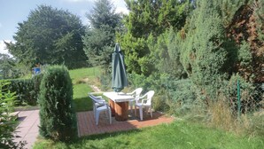 A garden patio with a table and chairs, surrounded by greenery and a fence. - 2 bedroom cozy home in Spitzkunnersdorf (Spitzkunnersdorf)