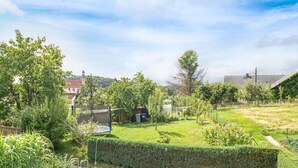 A residential backyard with a trampoline, a hedge, and a distant view of a church with a tower. - 2 bedroom cozy home in Spitzkunnersdorf (Spitzkunnersdorf)