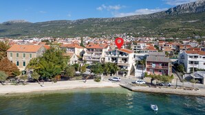 Une ville côtière dotée d’un port de plaisance, de bâtiments aux toits recouverts de tuiles rouges et bordée de montagnes.
