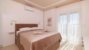 A bedroom with a bed, bedside lamps, a small table, and a window with curtains.