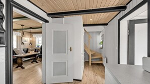Un interior moderno con techo de madera, una puerta blanca y una escalera.