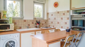 Kompakti keittiö, jossa on pesukone, mikroaaltouuni ja liesi.
