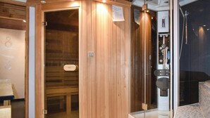 A sauna room with wooden walls and a glass door leading to a shower area.