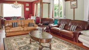 A spacious living room with leather sofas, a wooden coffee table, and a patterned rug.