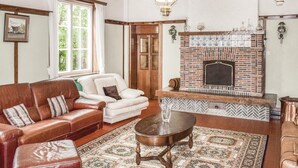 A cozy living room with a fireplace, leather sofas, a patterned rug, and a wooden coffee table.