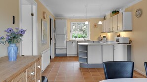 A compact kitchen with white cabinets, a built-in oven, and a window with a view of greenery.