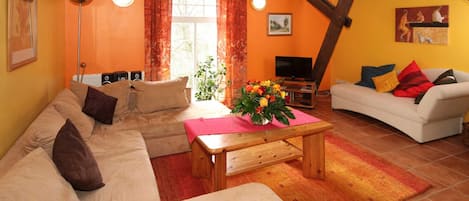 Una sala de estar acogedora con un sofá, una mesa de centro y un televisor.