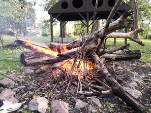 A campfire with logs and rocks, surrounded by a grassy area and trees. - Apartment 4 - The dog - Holidays at the castle Duckwitz (Behren-Lübchin)