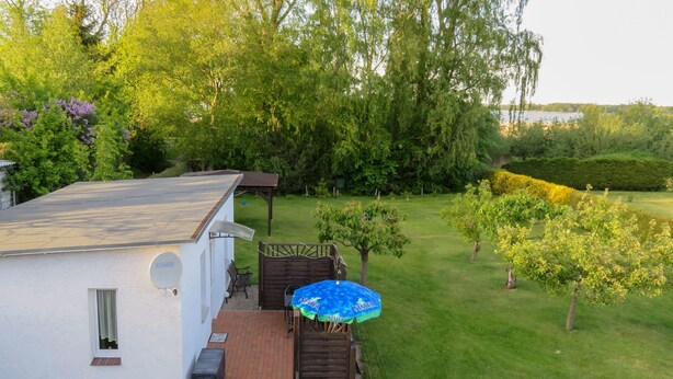 A white house with a patio, a small deck, and a blue umbrella. - Bungalow Alms, Germany (Ribnitz-Damgarten)