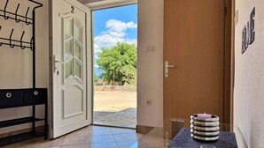 Habitación de hotel con puerta de madera, un banco, una mesa con velas y vistas a un patio.