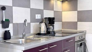 Una cocina moderna con un lavamanos de acero inoxidable, un hervidor y una cafetera.
