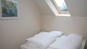 A bedroom with a skylight, a painting on the wall, and a neatly made bed with pillows. - 2 bedroom amazing apartment in Gudhjem (Gudhjem)