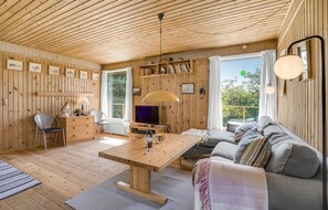 A cozy cabin interior with a wooden ceiling, a dining area with a table and chairs, a sofa, and a TV. - 3 bedroom beautiful home in Føllenslev (Føllenslev)