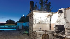 An outdoor kitchen area with a stone oven, a sink, and a pool in the background. - Stunning home in Betiga (Betiga)