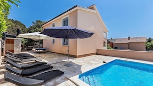 A poolside area with lounge chairs, a barbecue grill, and a covered seating area. - Stunning home in Betiga (Betiga)