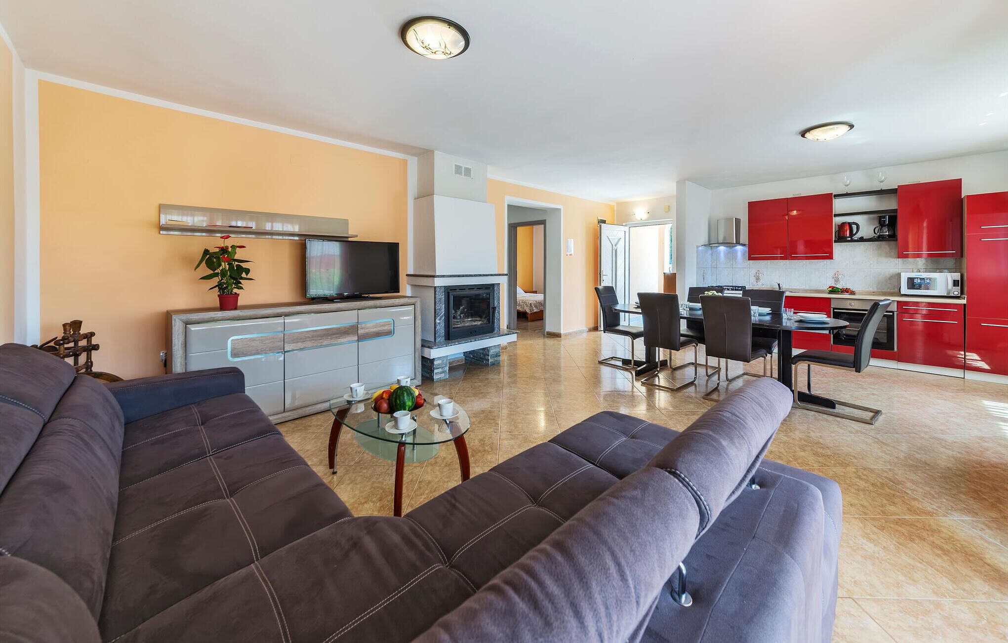 Ein modernes Wohnzimmer mit einer Couch, einem Fernseher, einem Kamin und einer Essecke mit roten Schränken.