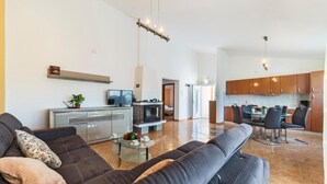 A modern living room with a sofa, TV, fireplace, and a dining area with chairs and a table. - Stunning home in Betiga (Betiga)