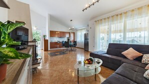 A modern living room with a sofa, a glass coffee table with fruit, and a TV in the background. - Stunning home in Betiga (Betiga)