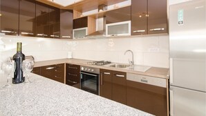 Une cuisine moderne dotée de plans de travail en granit, d’appareils électroménagers en acier inoxydable et de meubles de couleur marron.