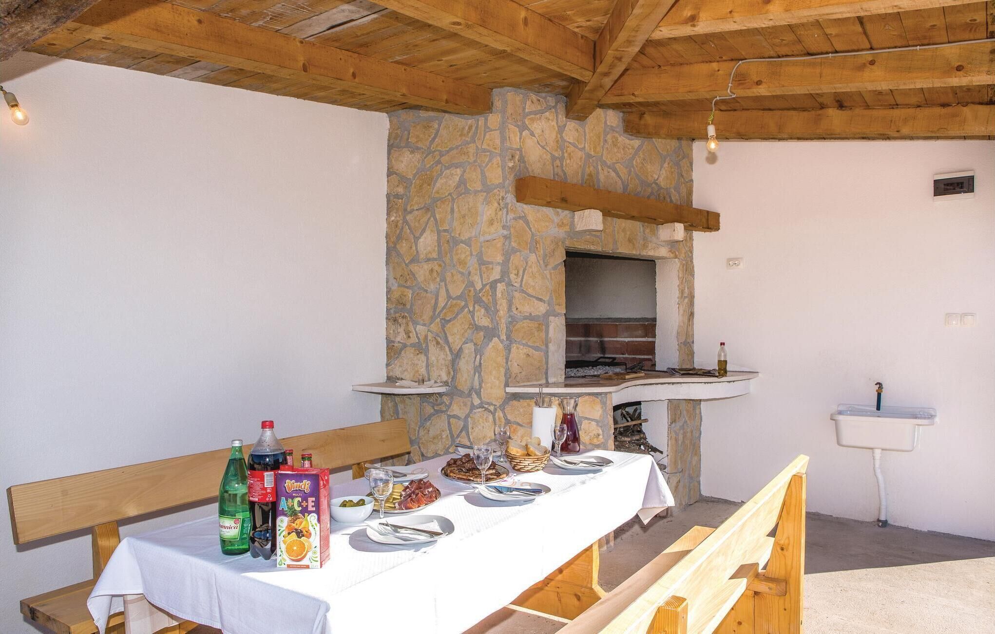 A rustic dining area with a stone wall, wooden beams, and a built-in pizza oven.