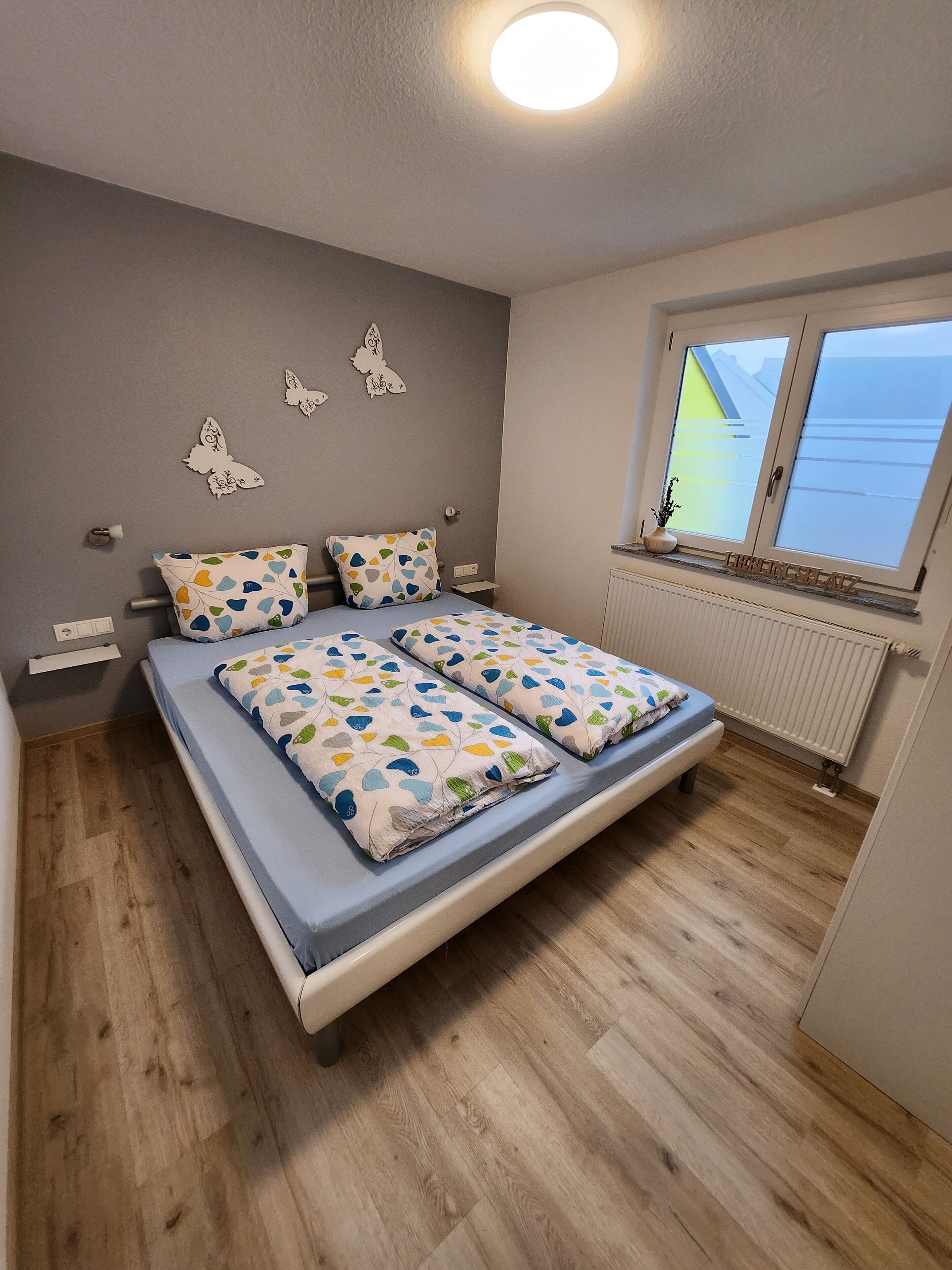 Ein Schlafzimmer mit Bett, Fenster und Heizkörper.