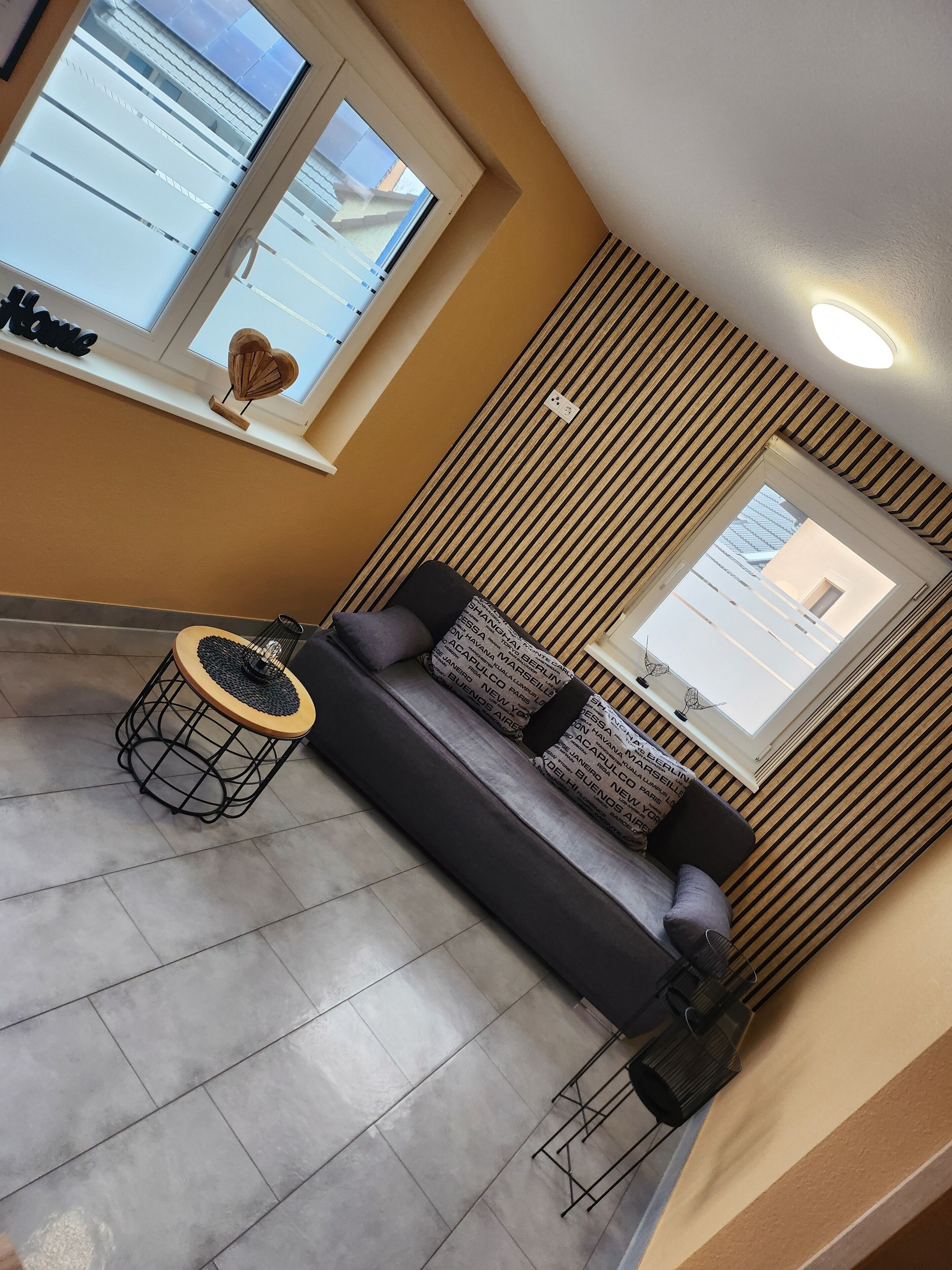 Ein modernes Wohnzimmer mit einer Couch, einem runden Couchtisch und einem Fenster mit Blick auf Gebäude.