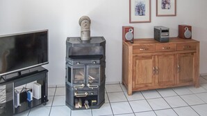 Una sala de estar con un estufa de leña negra, un mueble de madera y un televisor.