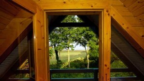 A wooden interior with a view of a green landscape through a doorway. - Ferienhaus Kranichblick am Bodden (Saal)