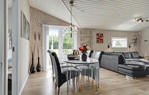 Ein modernes Wohnzimmer mit Esstisch, grauem Sofa und großem Fenster.