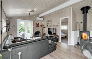 Ein modernes Wohnzimmer mit einer Couch, einem Fernseher und einem Kamin.