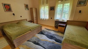 Ein Schlafzimmer mit zwei Betten, einem Holzschrank, einem Schreibtisch mit Stuhl und einem Fenster mit Vorhängen.