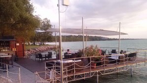 Ein Restaurant am Flussufer mit Terrassenplätzen, einer Bar und Blick auf das Wasser.