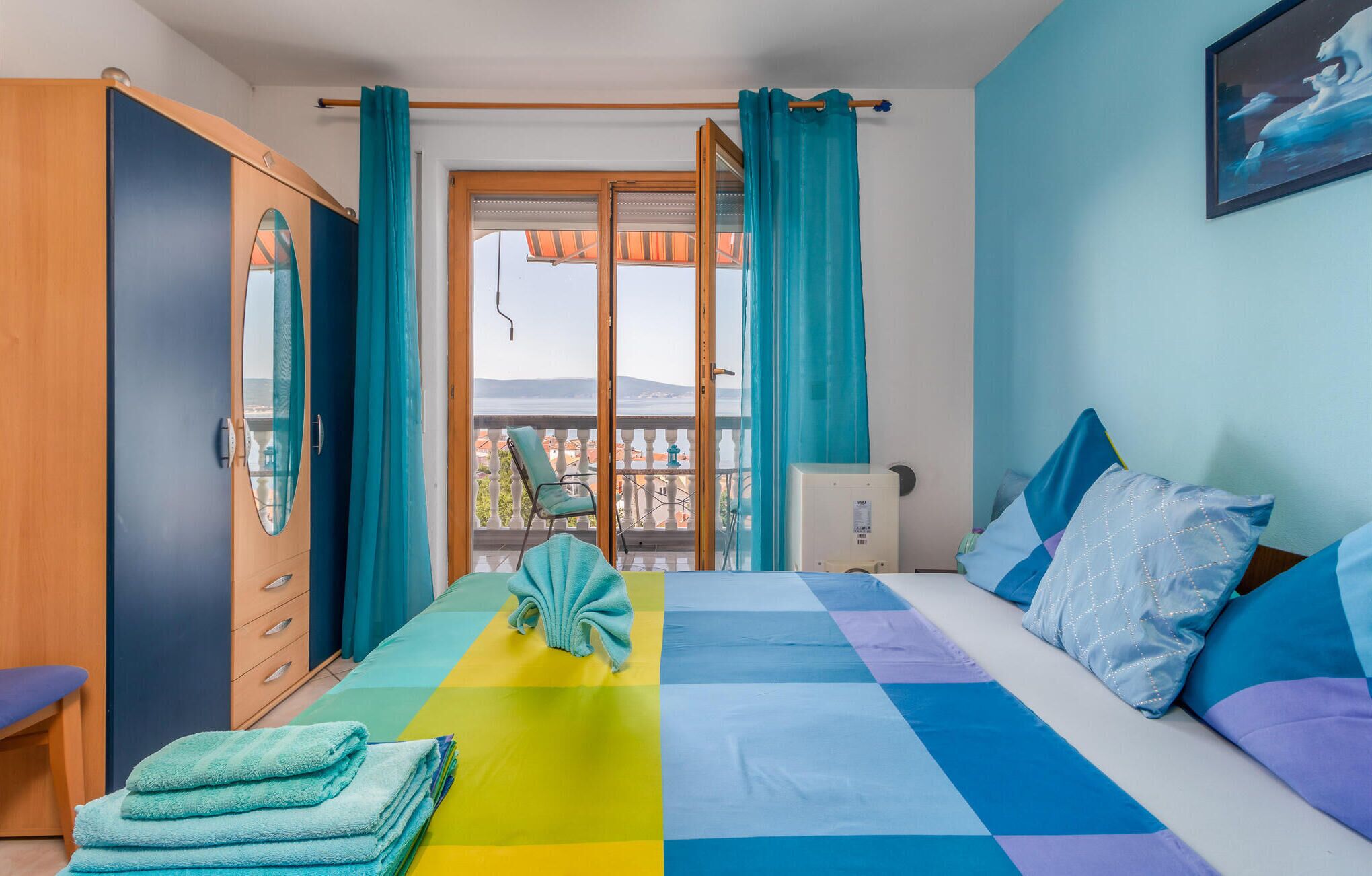 Ein Schlafzimmer mit Bett, Stuhl, Kleiderschrank und einem Balkon mit Blick.
