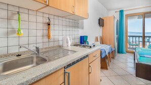 Een keuken met een granieten aanrecht, een roestvrijstalen spoelbak en houten keukenkastjes. Op het aanrecht staan een koffiezetapparaat, een waterkoker en een broodrooster.