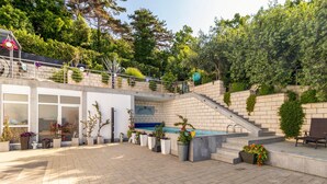 Een modern buitenpatio met een zwembad, stenen trappen en potplanten.