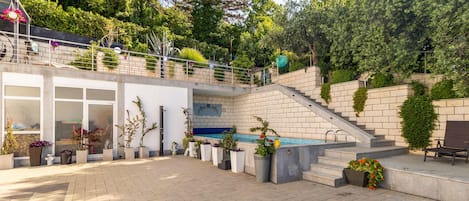A modern outdoor patio area with a pool, stone steps, and potted plants.