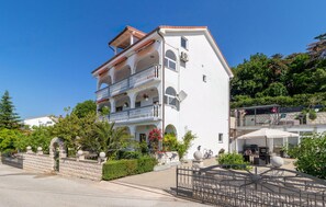 Um edifício com vários andares, varandas, portão fechado e área de estar externa.