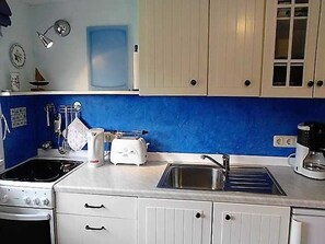 Una cocina con estufa, tostadora, pileta y alacenas.