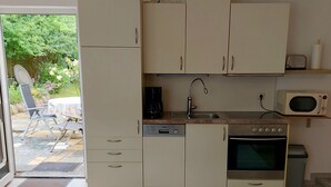 A compact kitchen with a dishwasher, oven, microwave, and a small sink. - Apartment Schwalbennest - House Gundelrebe (Bergen auf Rügen)