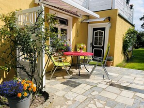 A patio with a table and chairs, a potted plant, and a door. - Apartment Schwalbennest - House Gundelrebe (Bergen auf Rügen)