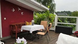 A covered outdoor dining area with a table and chairs, a bench, and a potted plant. - Apartment Schwalbennest - House Gundelrebe (Bergen auf Rügen)