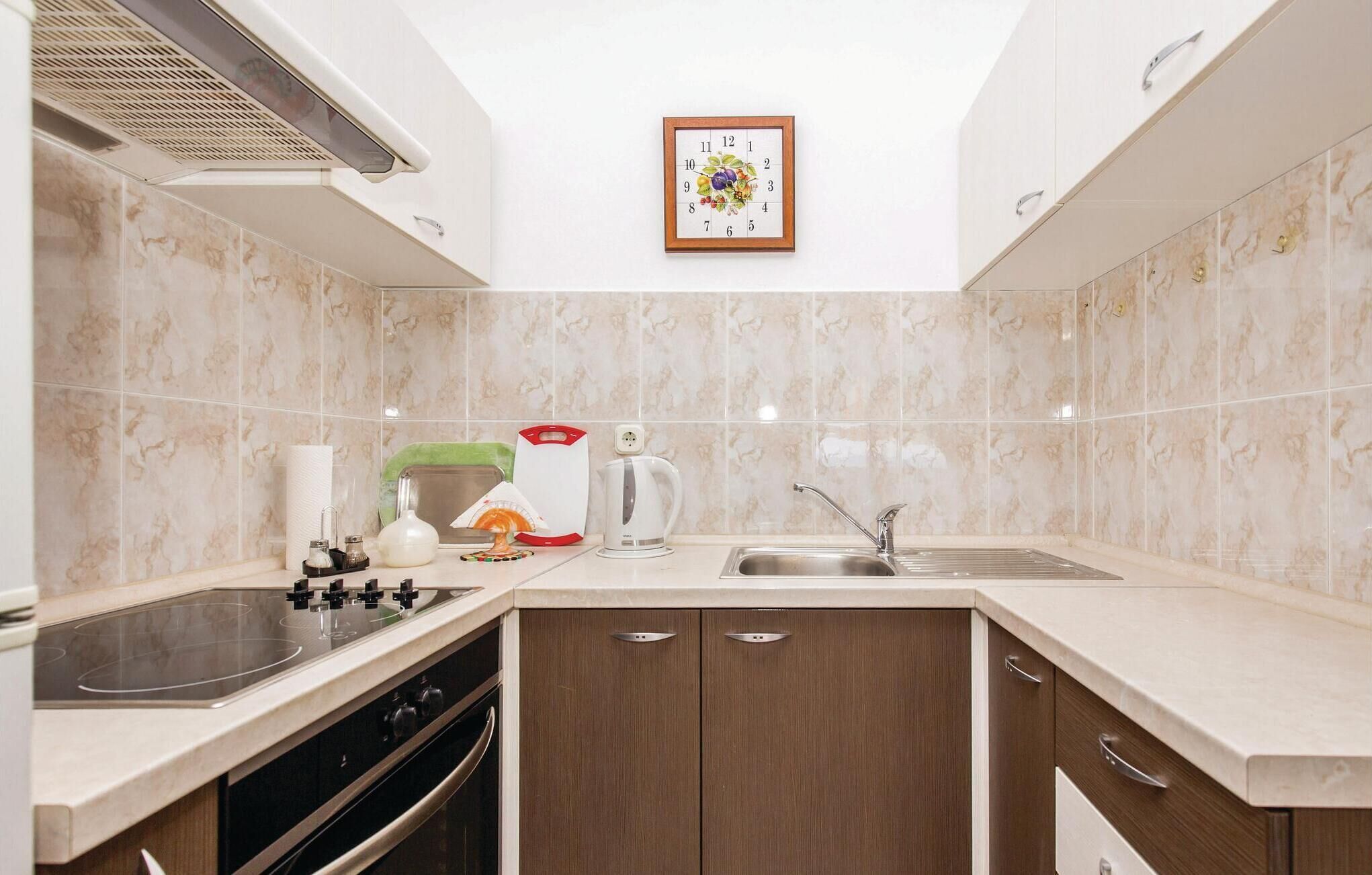 A modern kitchen with a built-in oven, a stovetop, a sink, and wooden cabinets.